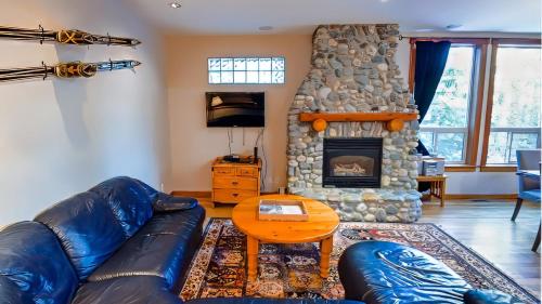 a living room with a couch and a stone fireplace at Polar Peak Chalet by Fernie Lodging Company in Fernie