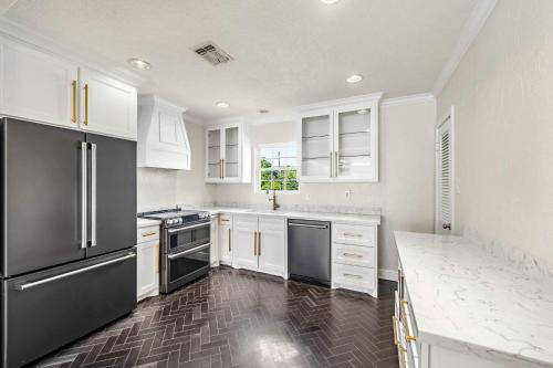 a kitchen with white cabinets and black appliances at The Bishop's Haven in Houston