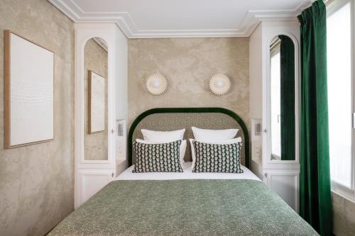 a bedroom with a large bed and two windows at Hotel des Carmes by Malone in Paris