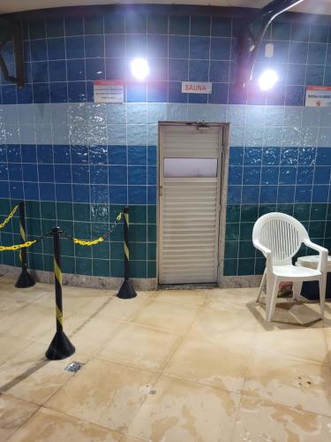 a blue tiled room with a door and a white chair at Residencial Privé das Thermas I in Caldas Novas