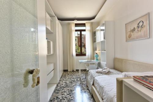 een slaapkamer met een bed, een bureau en een raam bij Soderini Splendor: First Floor Palazzo Charm at Castello Square in Venetië