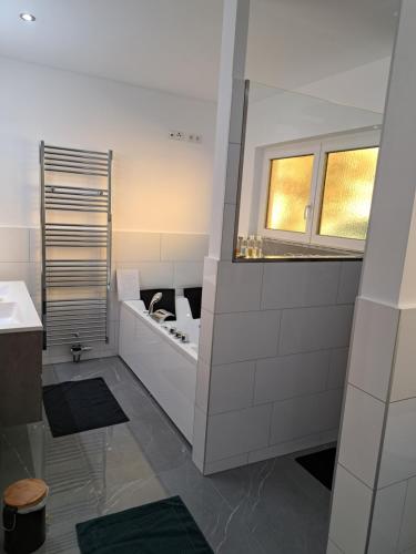 Baño blanco con lavabo y espejo en Ferienapartment "Zur Linde" en Breitenstein