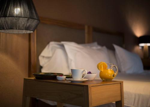 a table with cups and a yellow pitcher on a bed at Rosell Boher Winery Lodge & Spa in Agrelo