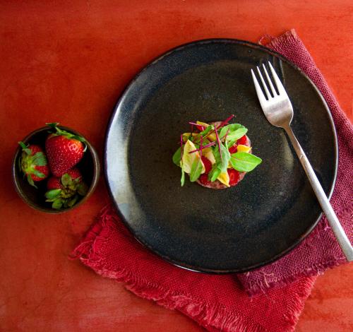 a black plate with a fork and a bowl of strawberries at Rosell Boher Winery Lodge & Spa in Agrelo