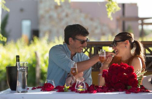 a man and woman sitting at a table with glasses of wine at Rosell Boher Winery Lodge & Spa in Agrelo