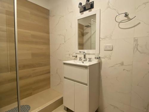 a white bathroom with a sink and a shower at Ubatuba Lofts Mar Azul - depto 2 hab in Mar Azul
