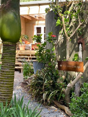 a garden with a sign that says the new garden at The Bay Cottage - Located Directly Across the Road from 2 Swimming Beaches in Great Barrier Island