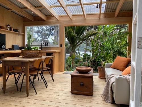 a kitchen and living room with a table and a couch at The Bay Cottage - Located Directly Across the Road from 2 Swimming Beaches in Great Barrier Island
