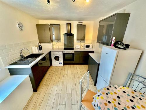 a small kitchen with a refrigerator and a sink at Stay in Whitechapel apartment in London
