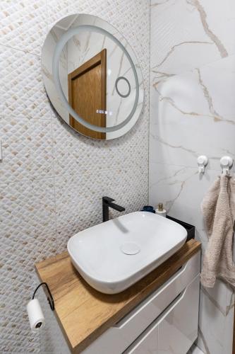 ein Badezimmer mit einem weißen Waschbecken und einem Spiegel in der Unterkunft 4 Ljubavi in Palić