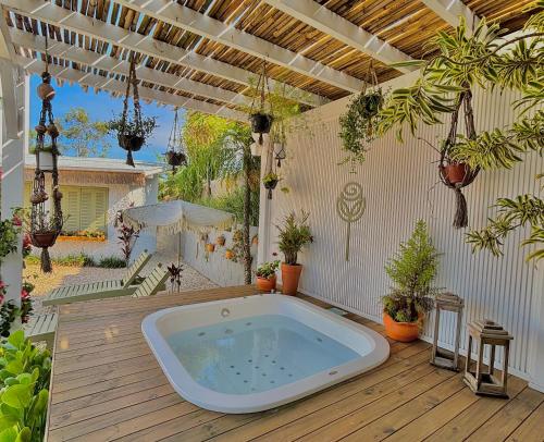 una vasca idromassaggio su una terrazza in legno con piante di Pousada Maria Parafina Praia do Rosa a Imbituba