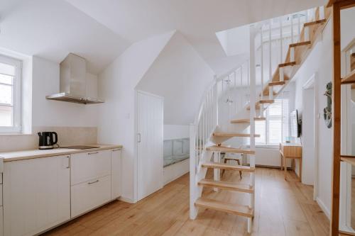 a kitchen with white cabinets and a wooden staircase at Villa Baltica Gdańsk in Gdańsk