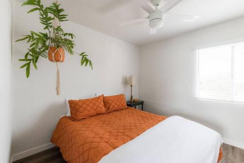 a bedroom with a bed with an orange comforter and a plant at Hidden Gem 1 Bdrm Top Floor Condo in San Diego