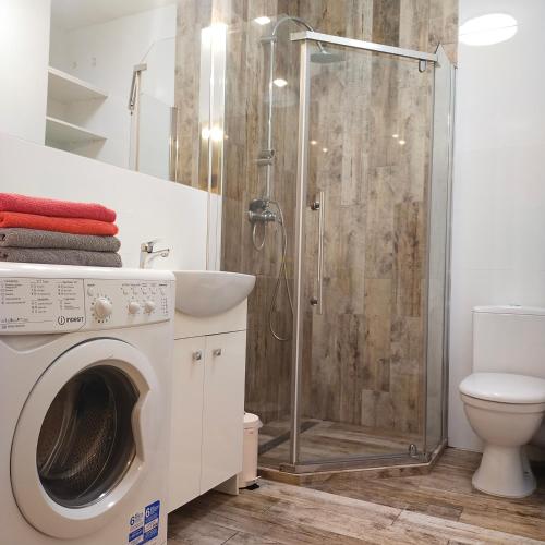 a bathroom with a shower and a washing machine at Black House in Jelitkowo