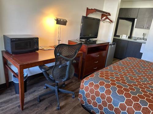 a room with a desk with a computer and a bed at Desert Sands Inn & Suites in Albuquerque