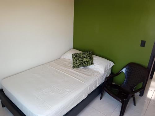 ein kleines Bett und ein Stuhl in einem Zimmer in der Unterkunft Habitación cerca al aeropuerto Matecaña in Pereira