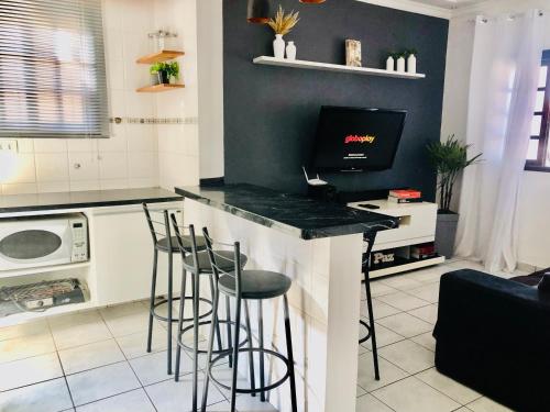 a kitchen with a bar with stools and a tv at Bertioga Casa pertinho da Praia in Bertioga