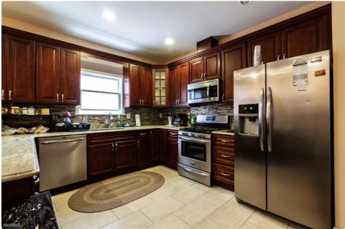 a kitchen with wooden cabinets and stainless steel appliances at Quiet apt only 15 mins away from Midtown Manhattan in Jersey City