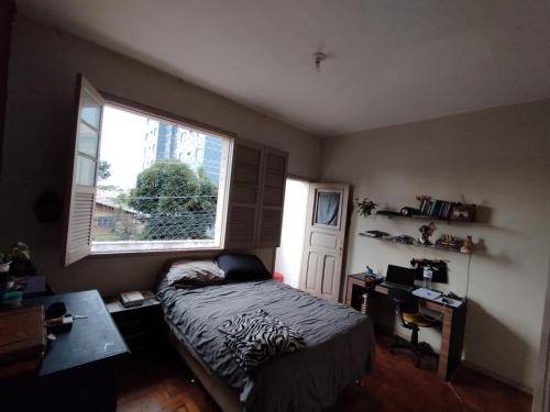um quarto com uma cama, uma janela e uma secretária em Apartamento Carnaval BH, Santa Teresa em Belo Horizonte
