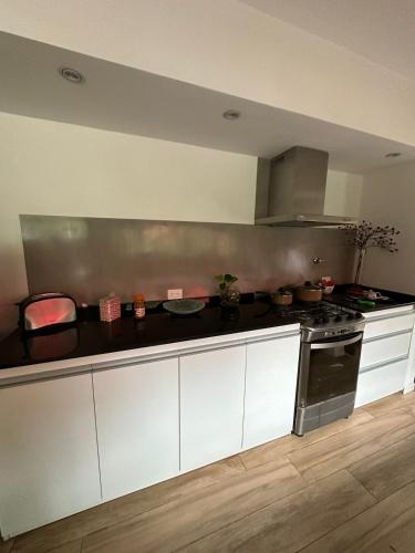 a kitchen with white cabinets and a stove at Hospedaje posada en Ezeiza in Ezeiza
