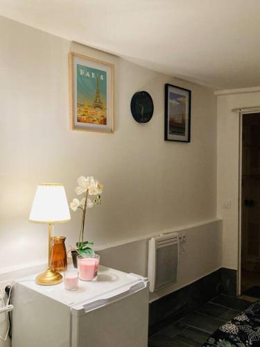 une pièce avec une table avec une lampe et des fleurs dessus dans l'établissement Studio house near paris, à Épinay-sur-Seine