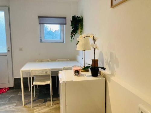 a room with a white table and chairs and a table with a lamp at Studio house near paris in Épinay-sur-Seine