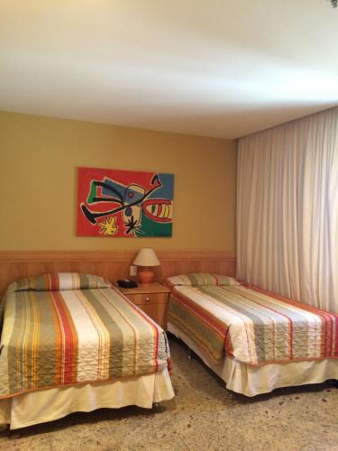 a hotel room with two beds and a painting on the wall at Tropical Barra Hotel in Rio de Janeiro