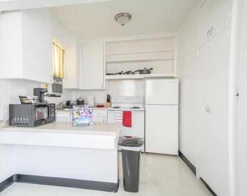 eine Küche mit weißen Schränken und einem weißen Kühlschrank in der Unterkunft Stay Condominiums Waikiki in Honolulu