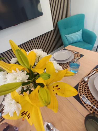 a vase of yellow and white flowers on a table at El Ramonal Vacacional in Candelaria