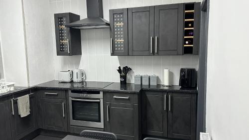 a kitchen with dark wooden cabinets and appliances at Modern 2 Bed near Turf Moor Football Stadium, Parks, Canal and Lake in Burnley