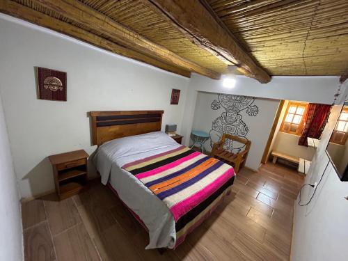 a bedroom with a bed with a colorful striped blanket at Puna Hostel in San Pedro de Atacama