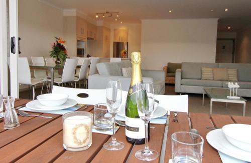 a bottle of wine sitting on a table with glasses at Crow's Nest Apartments in Whitianga