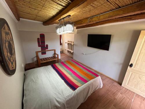 a bedroom with a bed and a flat screen tv at Puna Hostel in San Pedro de Atacama