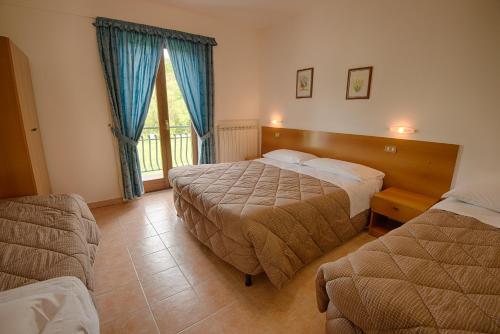 a hotel room with two beds and a window at Albergo Della Corte in Pescasseroli