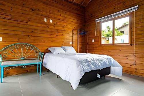 a bedroom with a bed and a chair and a window at Cabanas aconchegantes. Desfrute da natureza e praia in Florianópolis