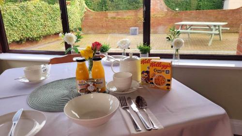 a table with a white table cloth and bottles of orange juice at Church Farm Guest House in Horsford