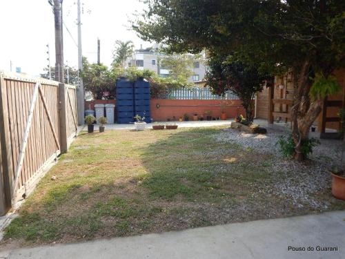 a yard with a fence and a tree at Pouso do Guarani - 200m do mar|wifi|Ar cond in Florianópolis