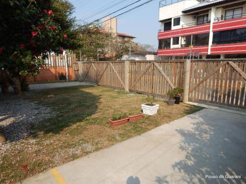 a backyard with a wooden fence and a garden at Pouso do Guarani - 200m do mar|wifi|Ar cond in Florianópolis