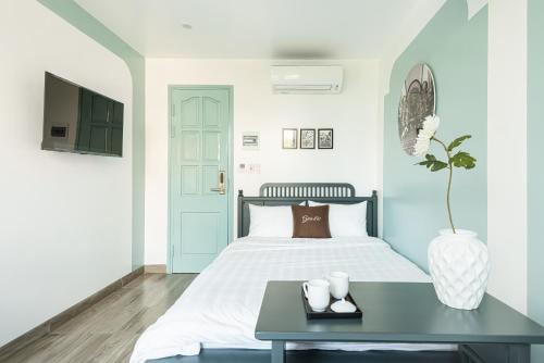 a white bedroom with a bed and a table at GARE D'47 Homestay/ Hotel in Hai Phong