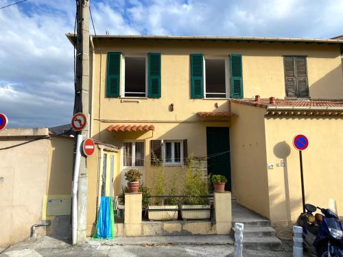 a yellow house with green shutters at Appartement La Maouin 2 pièces in Saint-Laurent-du-Var