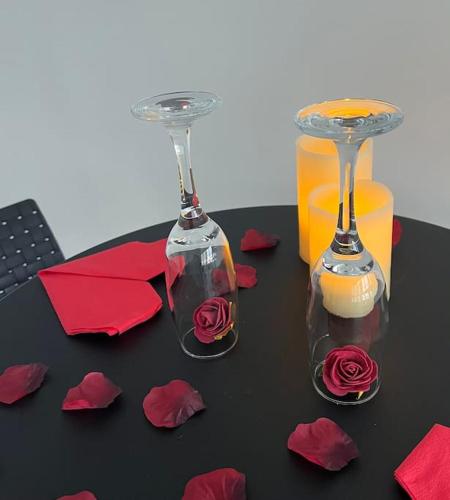 deux verres à vin avec des roses et du papier rouge sur une table dans l'établissement Suite « BODY LOVE » - Jacuzzi privatif, à Créteil