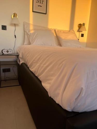 - un lit avec des draps et des oreillers blancs à côté d'une table dans l'établissement Suite « BODY LOVE » - Jacuzzi privatif, à Créteil