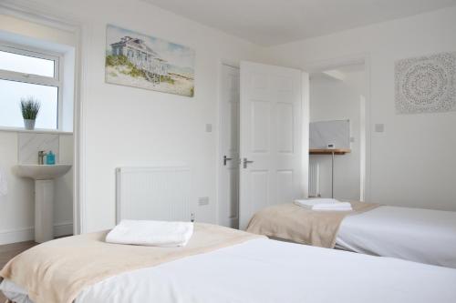 a white bedroom with two beds and a window at Parkside Apartment in Norwich