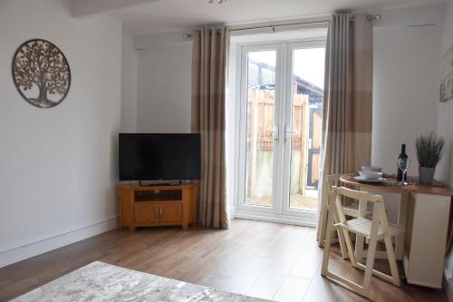 een woonkamer met een televisie en een tafel met een stoel bij Parkside Apartment in Norwich