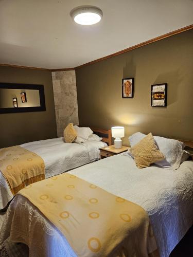 a hotel room with two beds with yellow sheets at Hotel Boutique Terra Diaguita & Spa in La Serena