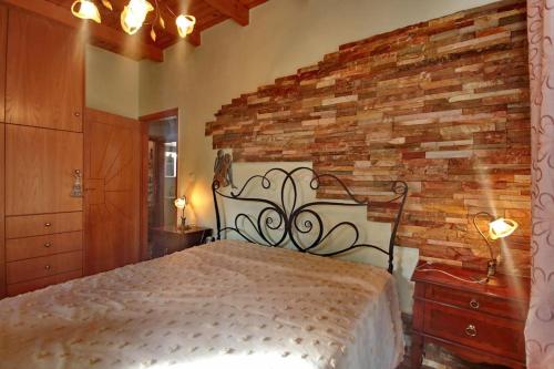 1 dormitorio con cama y pared de ladrillo en Ktima Karadimou, en Karkaloú