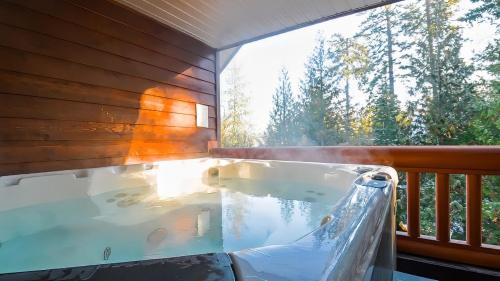 a hot tub on a balcony with a large window at Polar Peak Chalet by Fernie Lodging Company in Fernie
