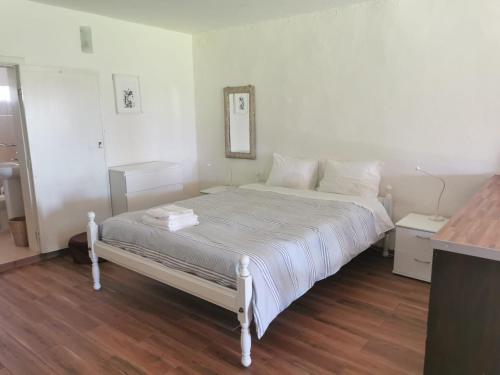 una camera con un letto bianco e pavimenti in legno di T0 da Casa da Quinta S José a Praia de Mira