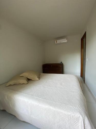 1 cama blanca en un dormitorio blanco con ventana en Chalé Oxente em Corumbau-BA en Corumbau