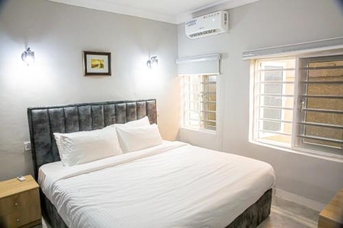 una camera da letto con un letto con lenzuola bianche e una finestra di Plot 100 a Lagos